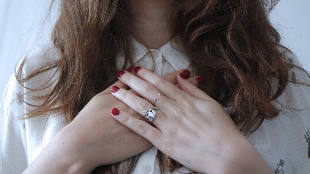 Person with eyes closed and hand on heart, soaking in emotion and light, symbolizing sensitivity and nervous system awareness.